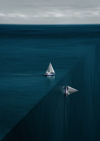 Two white-sailed yachts on a dark blue sea that turns vertically downwards along a sharp diagonal edge